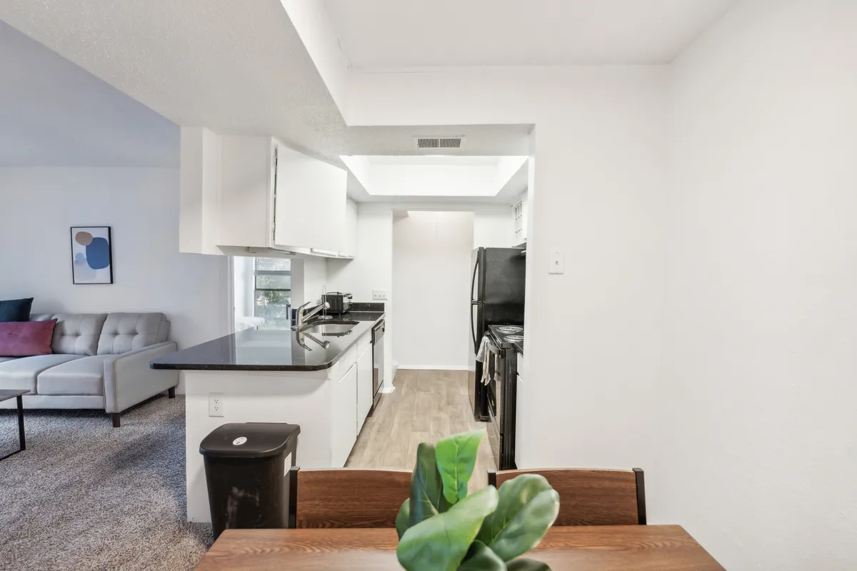 A modern, cozy open-plan living area featuring a kitchen counter, dining table, and comfortable sofa. The space looks perfect for hosting friends, enjoying meals, or relaxing after a day of exploring the city.