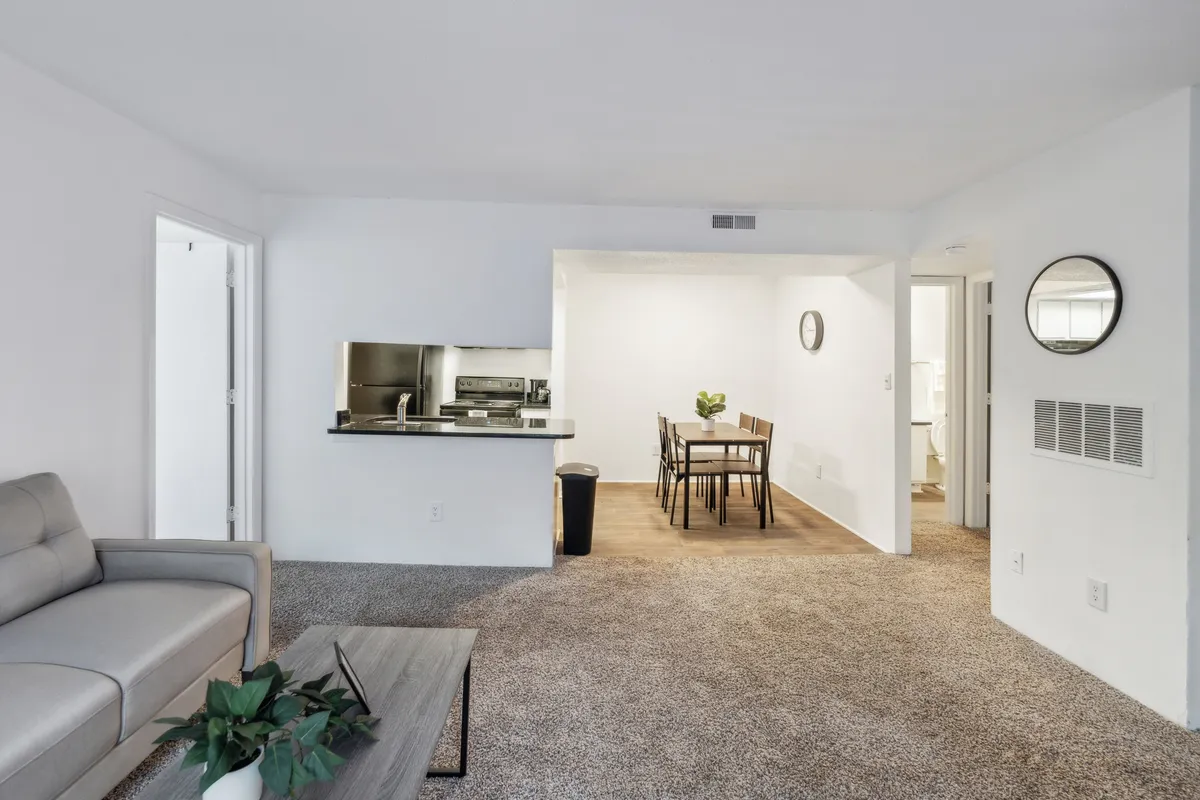 An open-plan view that connects the kitchen, dining, and living areas, featuring a dining table adjacent to the kitchen and a cozy sofa nearby. The space feels welcoming and homey, ideal for entertaining or relaxing while staying connected to loved ones.