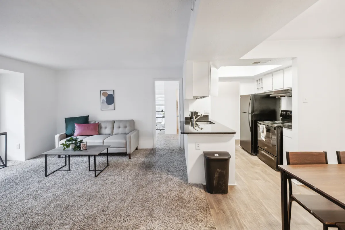 A warm and inviting interior with a modern sofa, a stylish dining table near the kitchen area, and eye-catching artwork on the wall. The setup invites both relaxation and gatherings, while the layout emphasizes how the living and dining spaces are interconnected for social events or quiet evenings in.