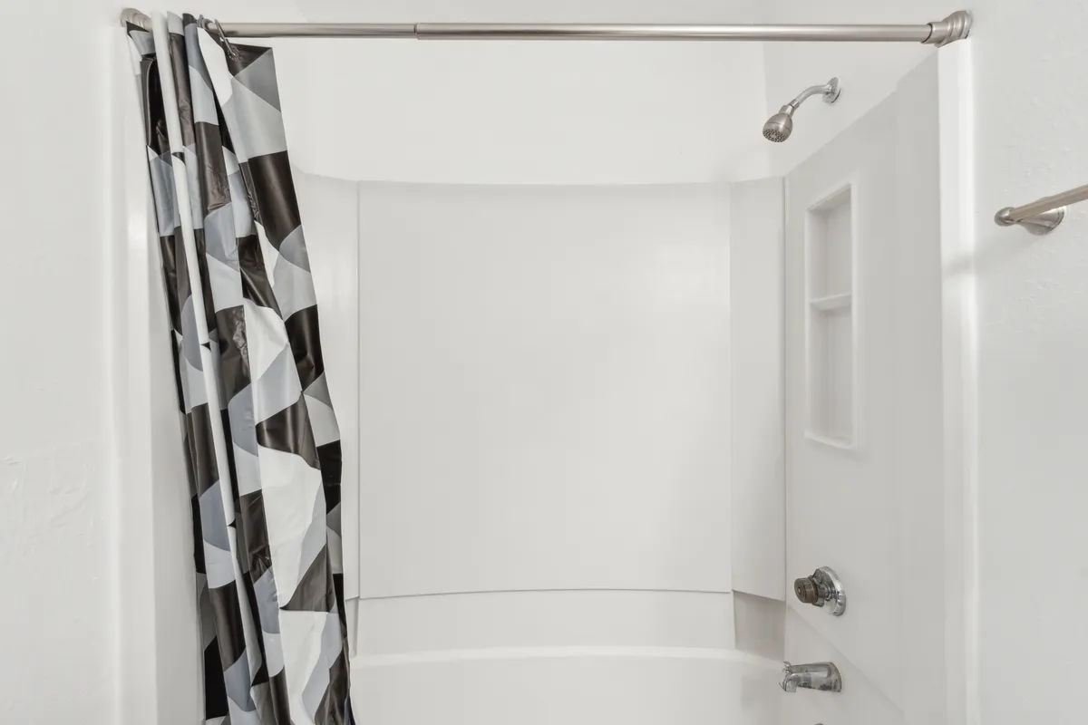 A refreshing bathroom scene with a bathtub, elegant shower curtain, and well-placed shower head. The mood is tranquil and inviting, offering a sense of relaxation and rejuvenation.