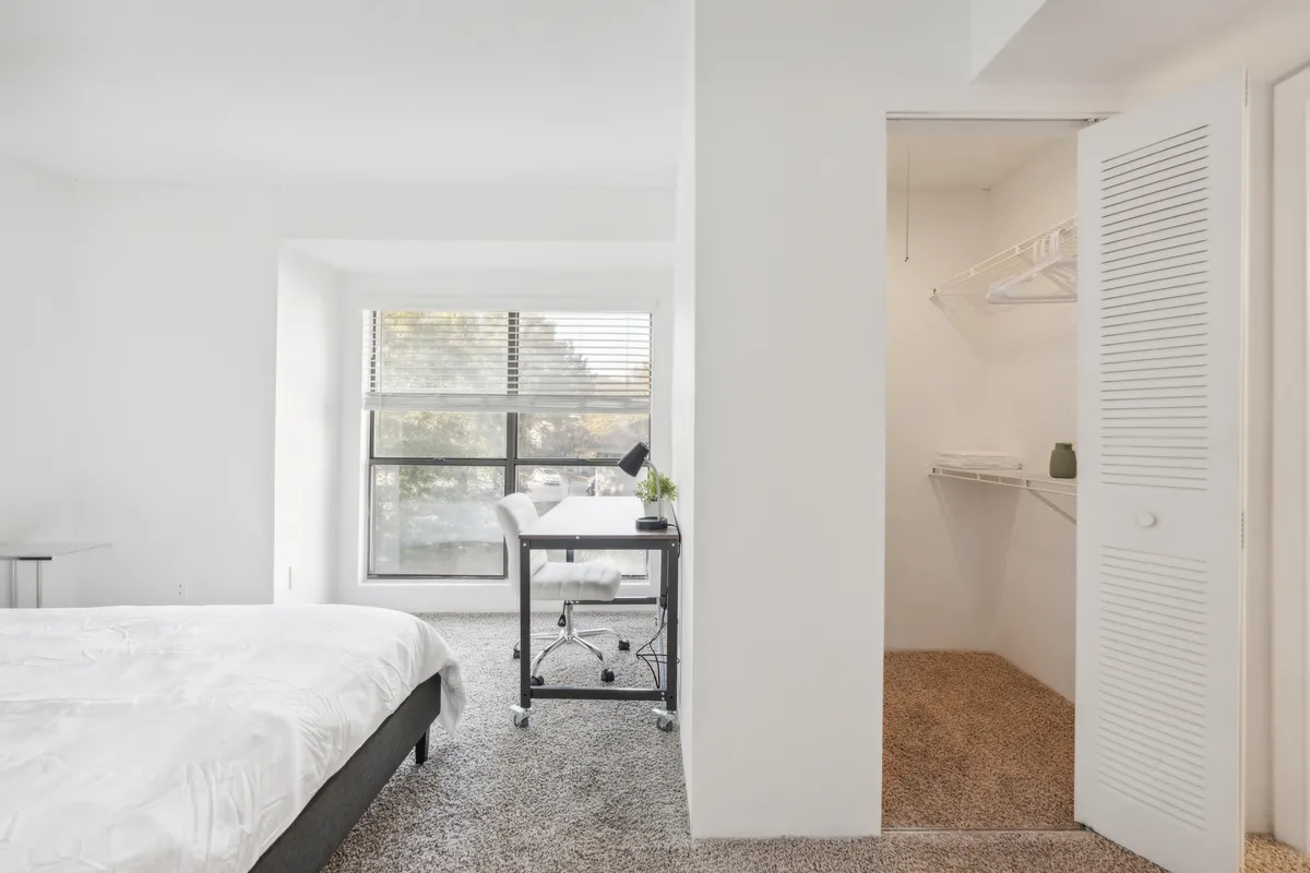 A bright and serene bedroom featuring a comfortable bed, a writing desk, and a sunlit window. The space is inviting, with natural light pouring in, suggesting a restful spot to return to after a day of exploration.