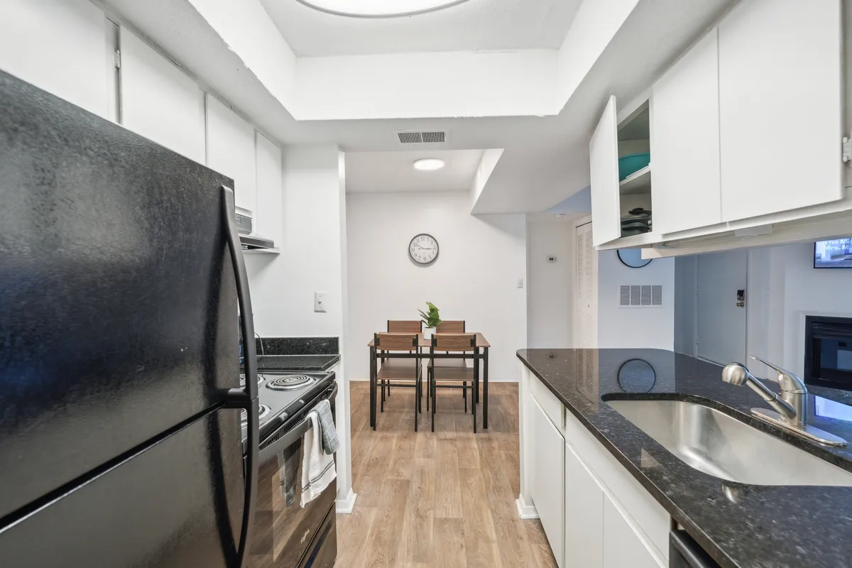 A stylish, inviting kitchen with a sleek black refrigerator, a clean countertop, and a dining table. The space is designed for both cooking and socializing, emphasizing comfort and readiness for daily living.